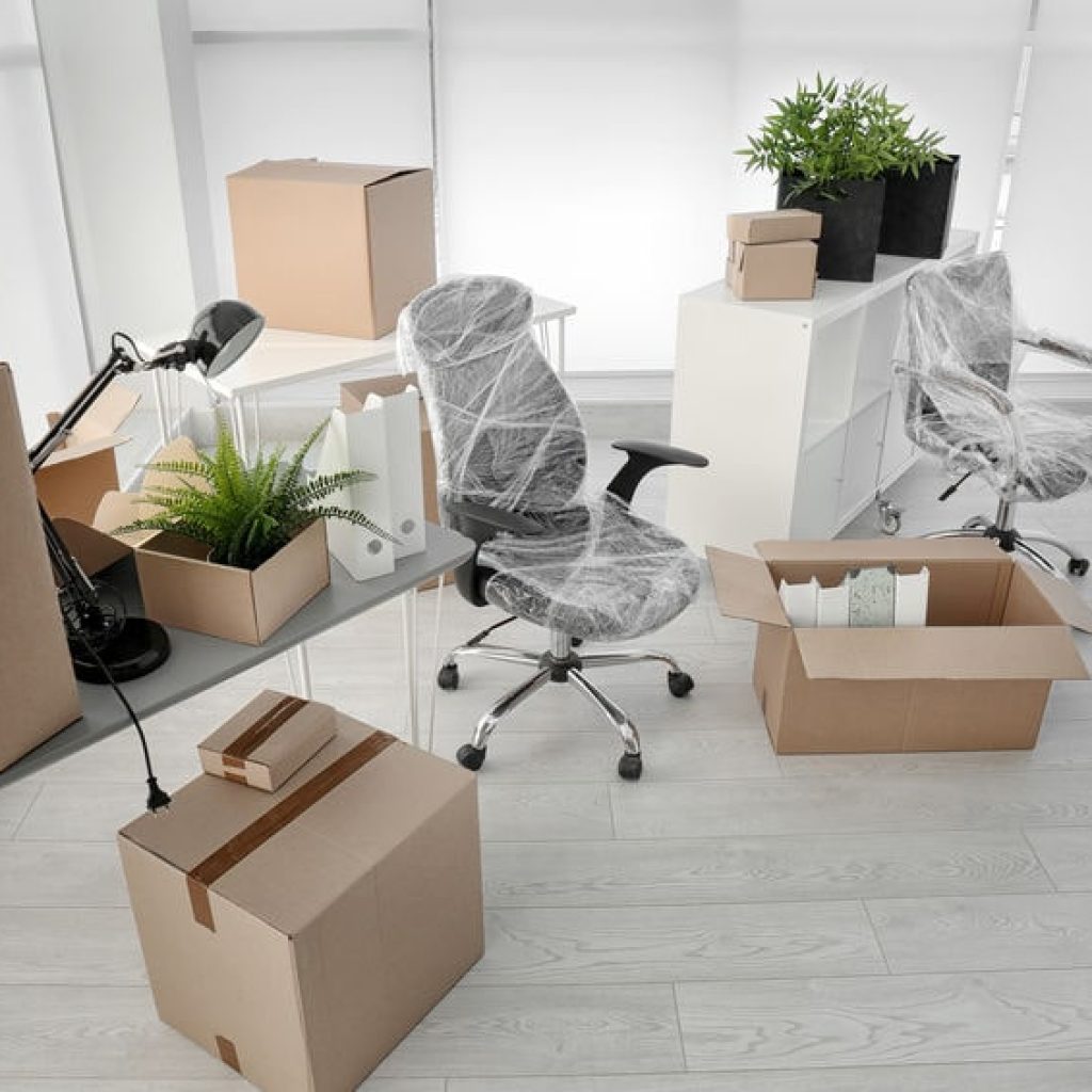 Office furniture and boxes packed for relocation, highlighting the cost and hassle compared to serviced offices in Singapore.